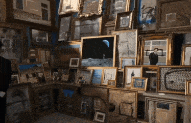 a room filled with lots of framed pictures including one of a man standing on the moon
