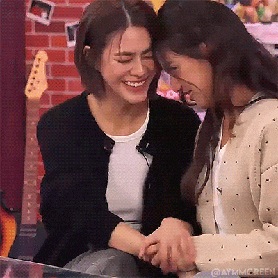 two women are holding hands and smiling at each other