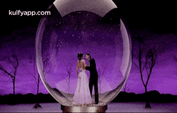 a man and woman are kissing in a snow globe .