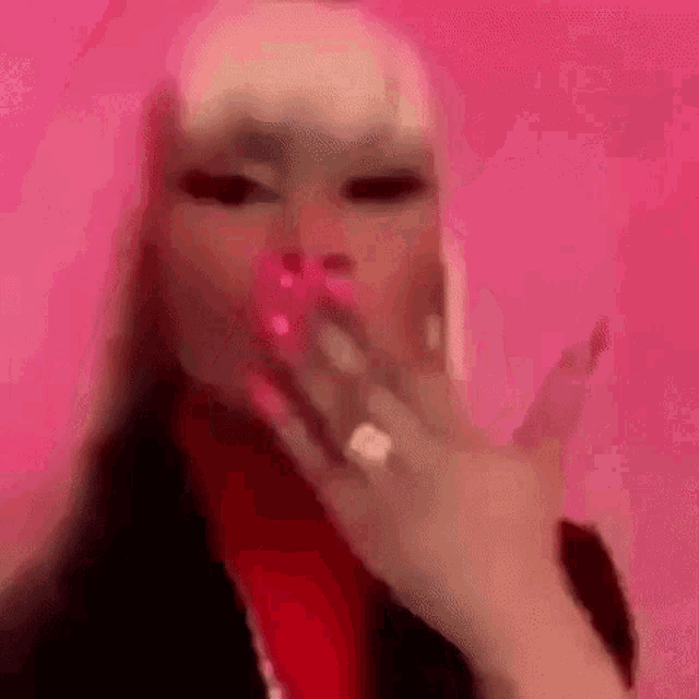 a blurry picture of a woman blowing a kiss with a pink background .