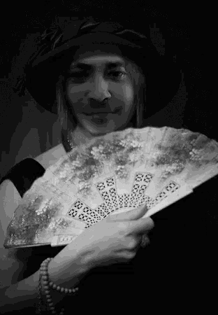 a woman in a hat is holding a fan in her right hand