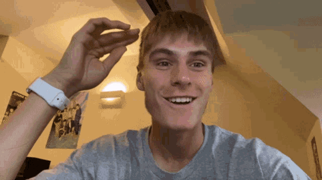 a young man wearing a grey shirt and a white watch holds something in his hand