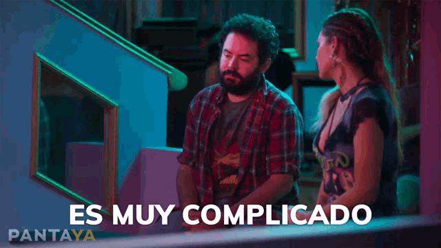 a man and a woman are sitting next to each other and the words es muy complicado are visible