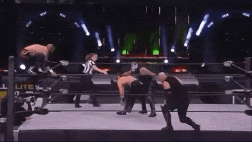 two men are wrestling in a wrestling ring while a referee looks on .