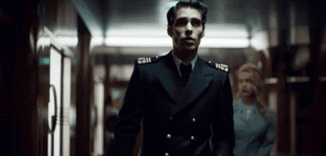 a man in a military uniform is walking down a hallway