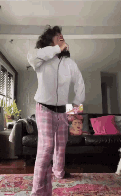 a woman in pink pajamas is dancing in front of a couch