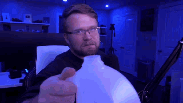 a man with glasses is pointing at a bottle of water