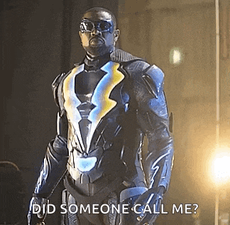 a man in a superhero costume is standing in front of a light .