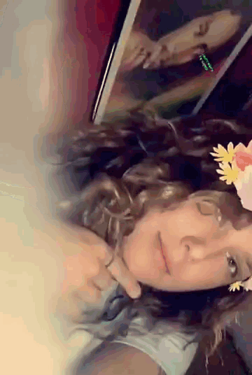 a woman wearing a flower crown looks at a picture of a woman