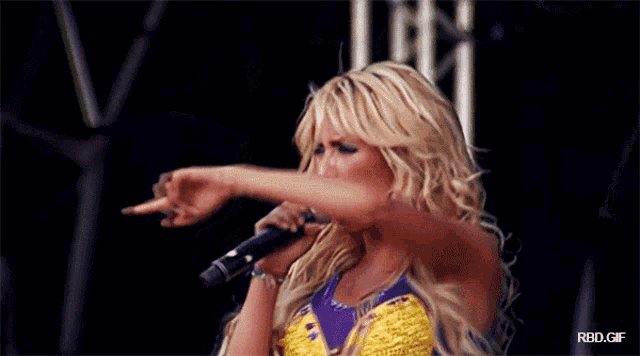 a blonde woman singing into a microphone with a rbd.gif watermark