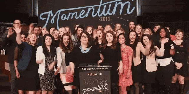 a group of people are posing in front of a sign that says momentum