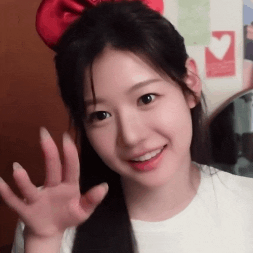 a girl with a red bow in her hair is waving