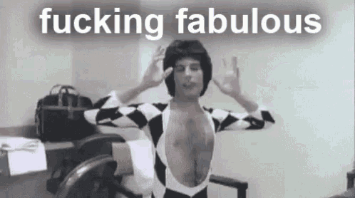 a man in a harlequin suit is standing in a room with his arms outstretched .