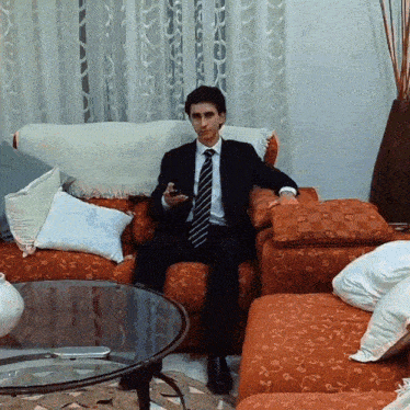 a man in a suit and tie sits on a couch