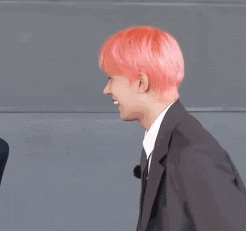 a man with pink hair is wearing a suit and tie and dancing .