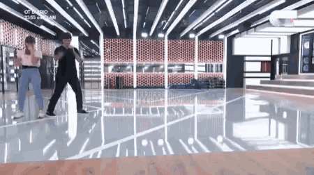 a man and a woman are dancing in a room with a lot of lights on the ceiling .