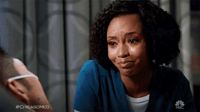 a woman with a tear running down her cheek is wearing a nbc shirt
