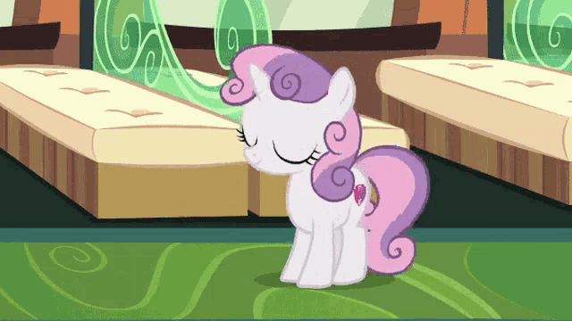 a cartoon pony with a pink mane and tail is sitting on a green carpet