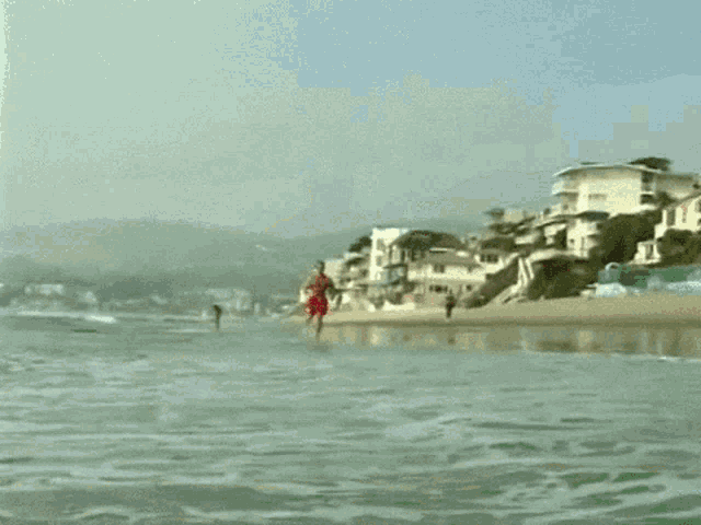 a man in red shorts is running along the beach