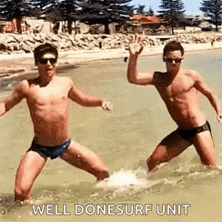 two men in swimsuits are standing in the water on a beach .