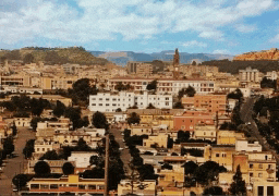 an aerial view of a city with a clock tower and mountains in the background