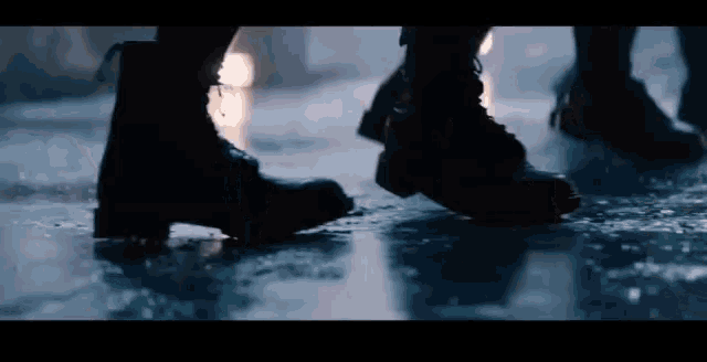 a close up of a person 's feet in black boots on a wet floor