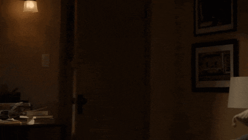 a woman is holding a large wooden bat in her hand in a dark room .