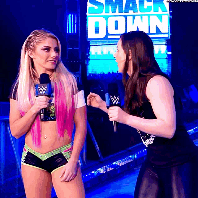 two women talking in front of a smack down sign