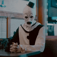 a clown wearing a top hat sits at a table