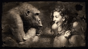 a woman is sitting next to a gorilla and smiling .