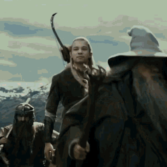 a man with a bow and arrow stands next to a man with a beard