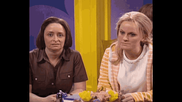 two women are sitting at a table with a cake
