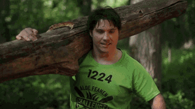 a man in a green shirt is pushing a large log