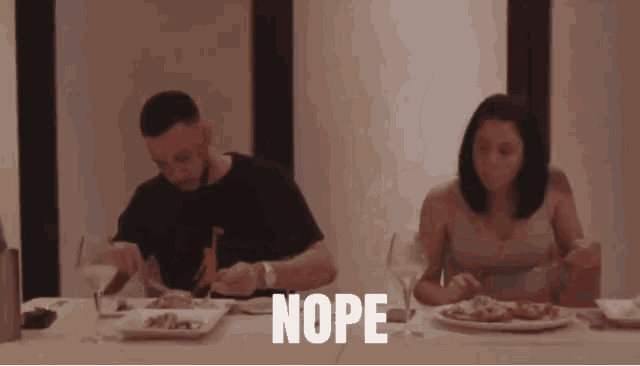 a man and a woman are sitting at a table with plates of food and glasses of wine and the word nope is above them