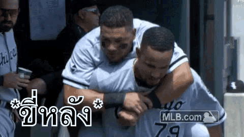 two baseball players are hugging each other in a dugout .