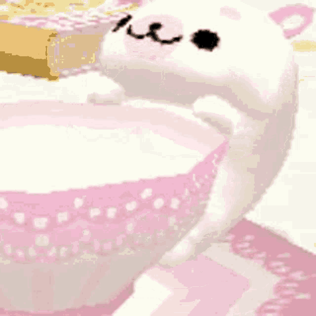a cartoon cat is sitting in a pink and white bowl of milk .