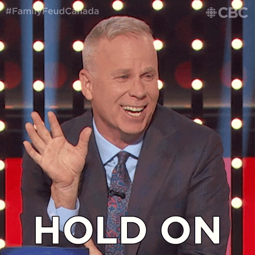 a man in a suit and tie is waving his hand and says hold on