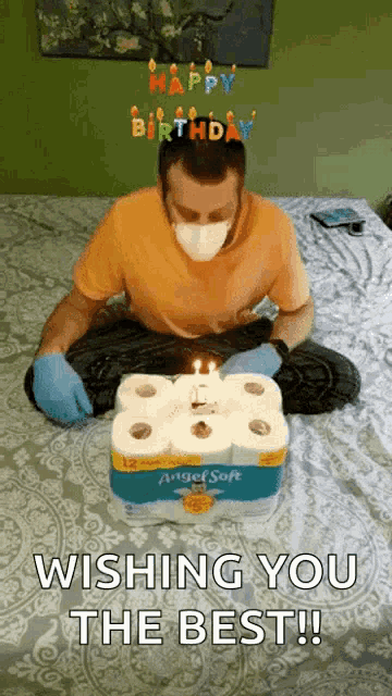 a man wearing a mask and gloves is sitting on a bed with a birthday cake made out of toilet paper