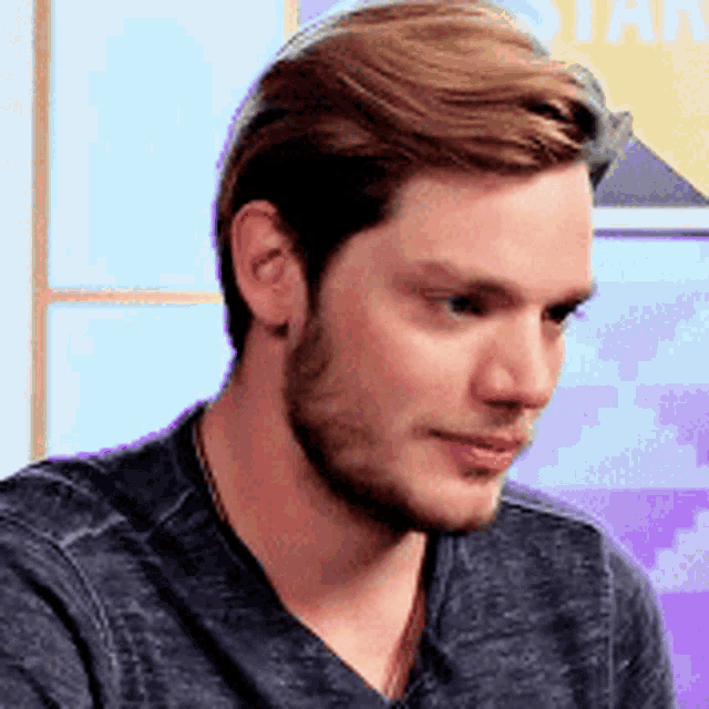 a close up of a man 's face with a beard wearing a gray shirt .