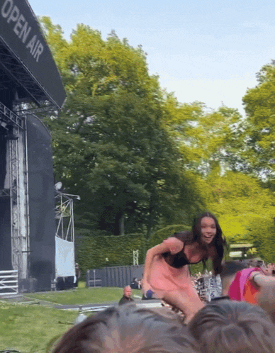 a woman in a pink dress is dancing in front of an open air sign