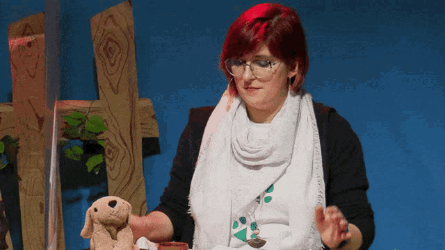 a woman wearing glasses and a white scarf is holding a stuffed animal