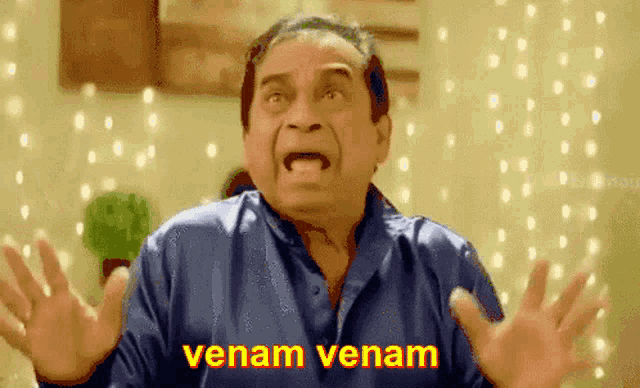 a man in a blue shirt is making a funny face and the words venam venam are above him .
