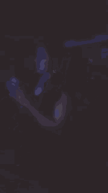 a woman is dancing in a dark room with blue lights