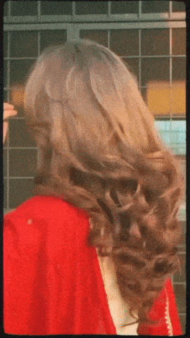 a woman 's hair is blowing in the wind and she is wearing a red shirt
