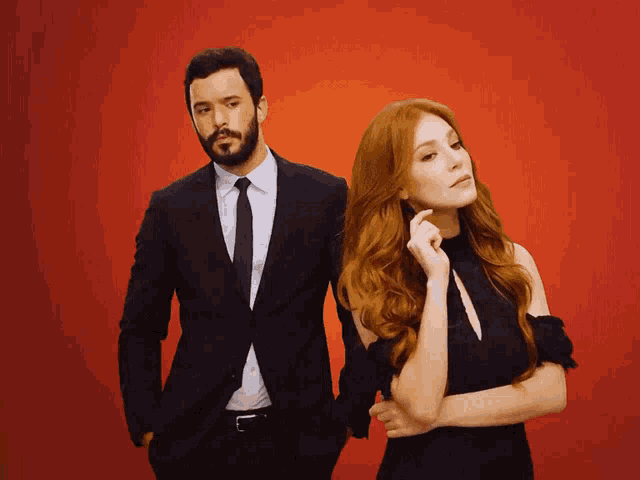 a man in a suit and tie is standing next to a woman with red hair