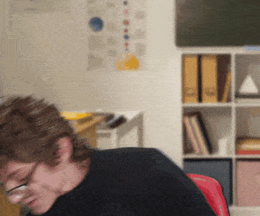 a blurry picture of a person sitting in front of a bookshelf