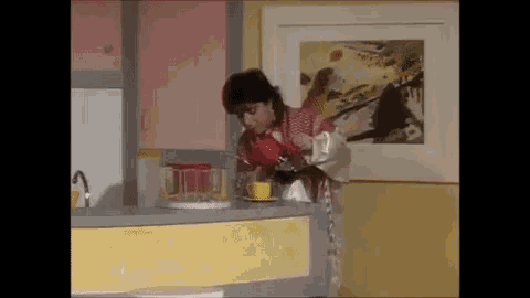 a woman is pouring a cup of coffee into a kitchen counter