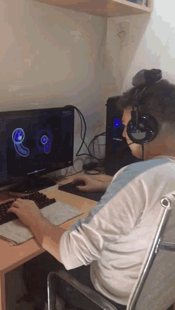 a man wearing headphones sits in front of a computer monitor