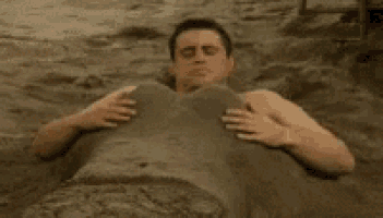 a man is buried in a pile of sand on the beach .