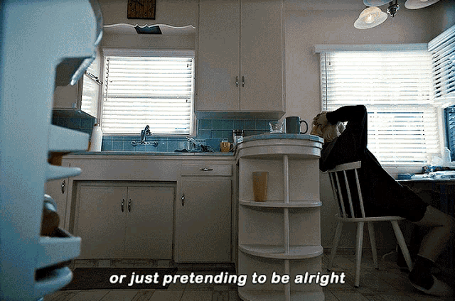 a woman sits in a chair in a kitchen with the words or just pretending to be alright below her